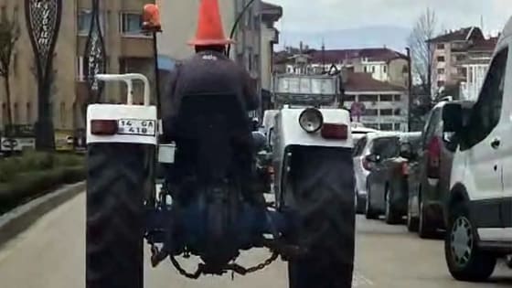 Trafikte şoke eden manzara! Başına trafik dubası geçiren traktör sürücüsü herkesi kahkahaya boğdu!