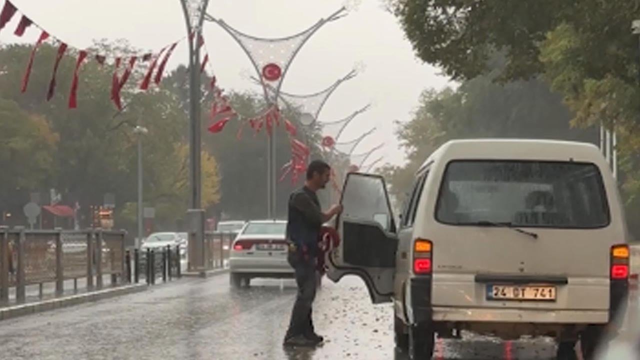 Yere düşen bayrakları yağmur altında tek tek topladı