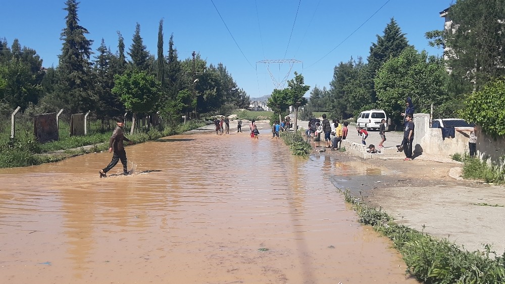 Çocukların patlayan borudan akan suda çamurla oyunu 