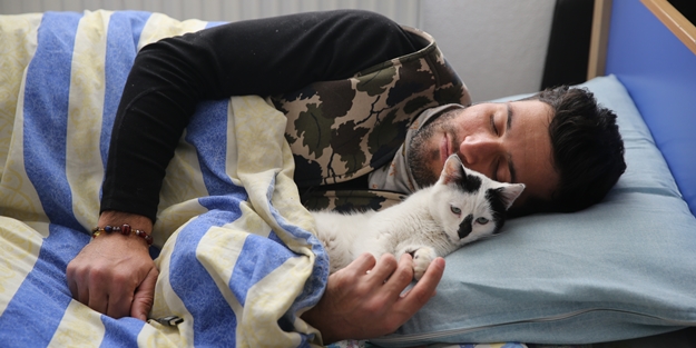 Enkazdan kurtararak sahiplendiği kediyi kucağından düşürmüyor