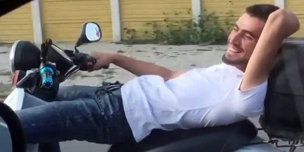 Koltuğuna sırt üstü yattığı motosikleti tek elle kullandı