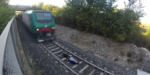 Raylara uzanıp trenin gelmesini bekledi