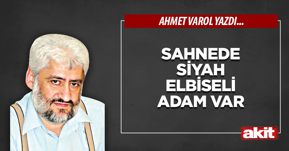 Sahnede siyah elbiseli adam var